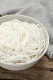 Photo of Bowl with cooked rice noodles on wooden table, closeup