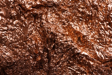 Photo of Crumpled rose gold foil as background, closeup view