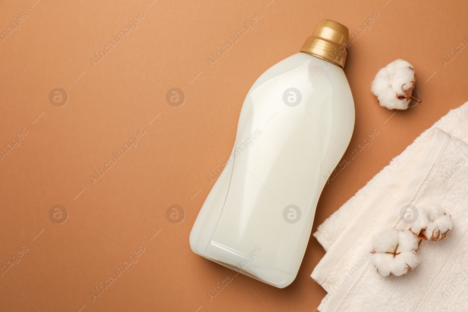 Bottle of fabric softener, terry towels and beautiful cotton flowers on brown background, flat lay. Space for text Photo of Bottle of fabric softener, terry towels and beautiful cotton flowers on brown background, flat lay. Space for text