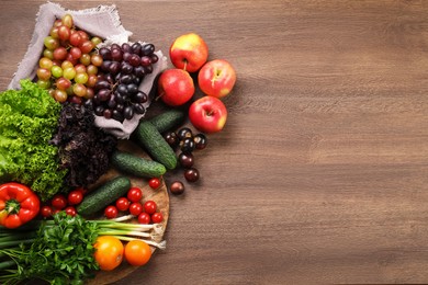 Photo of Different fresh ripe vegetables and fruits on wooden table, flat lay. Space for text