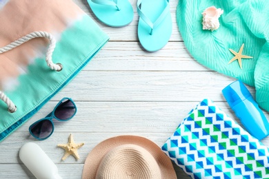 Flat lay composition with beach accessories on wooden background. Space for text