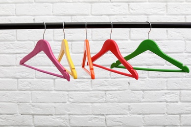 Photo of Clothes hangers on metal rail against brick wall background