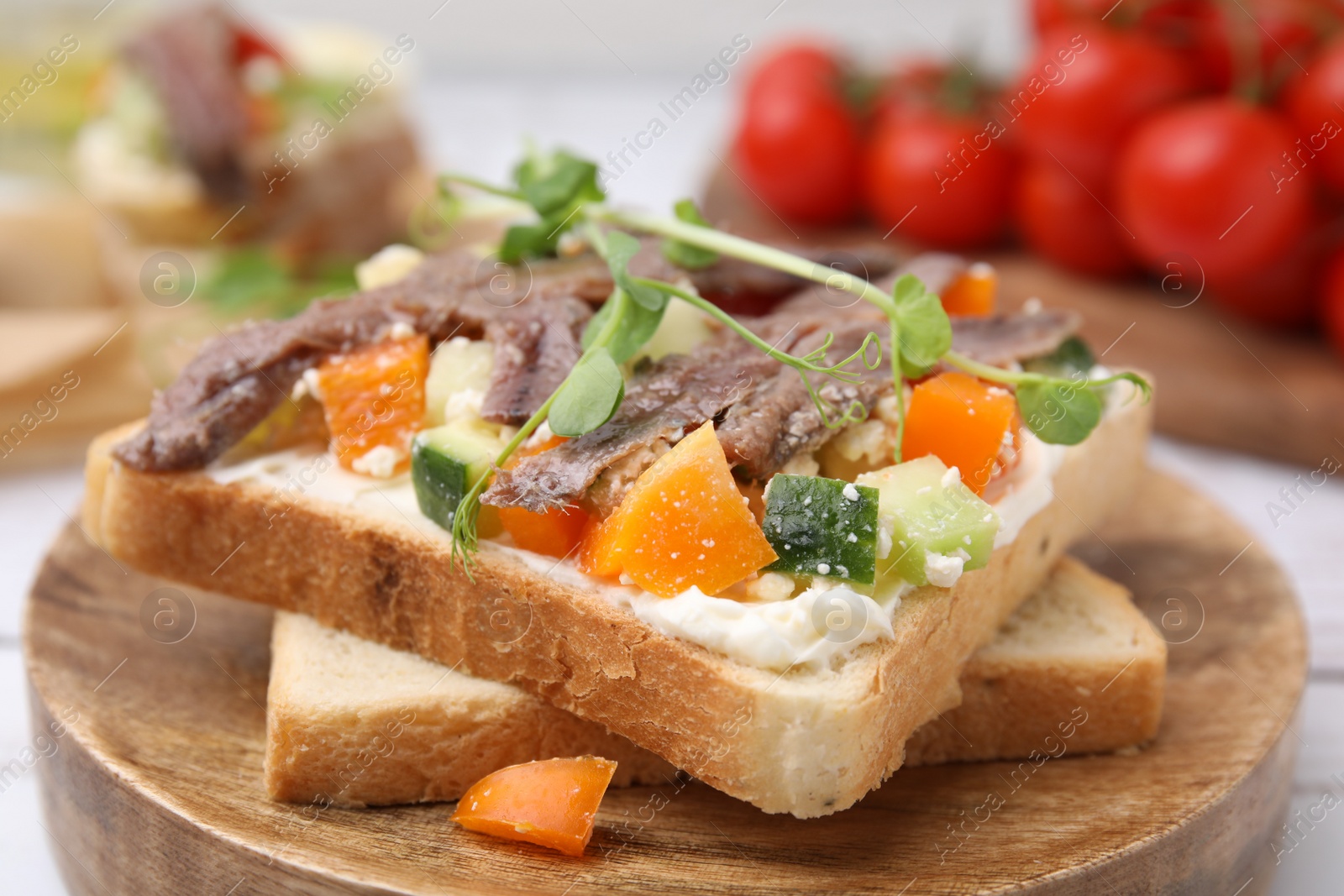 Photo of Delicious toasts with anchovies, cream cheese, bell peppers and cucumbers on white table, closeup