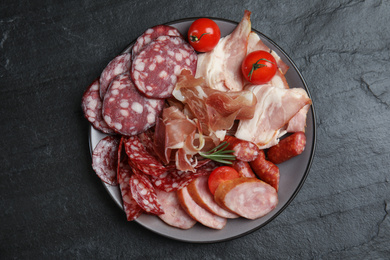 Different types of sausages with tomatoes served on black table, flat lay