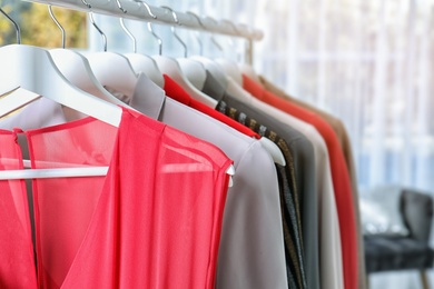 Photo of Stylish clothes hanging on wardrobe rack indoors, closeup