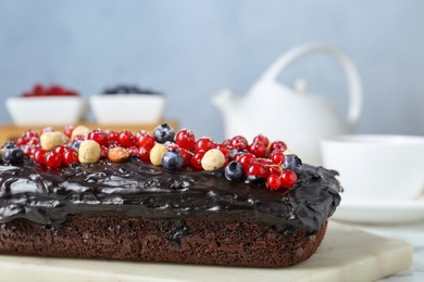 Photo of Delicious chocolate sponge cake with berries and nuts on table, closeup
