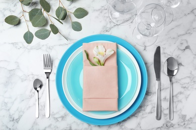 Beautiful table setting with cutlery, glasses, napkin and plates on marble background, top view