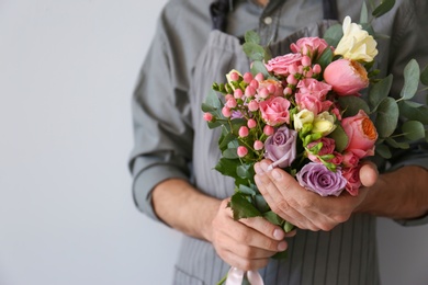 Male florist with beautiful bouquet on light background