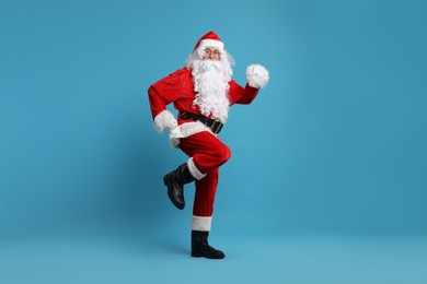Photo of Merry Christmas. Santa Claus posing on light blue background