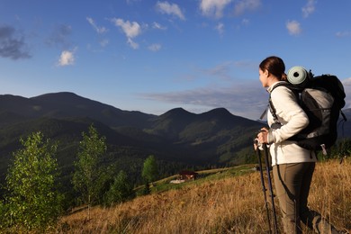Tourist with backpack and trekking poles enjoying mountain landscape, space for text