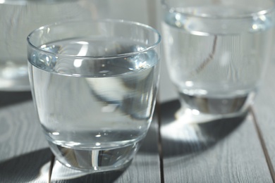Glass of water on grey wooden table, closeup. Refreshing drink