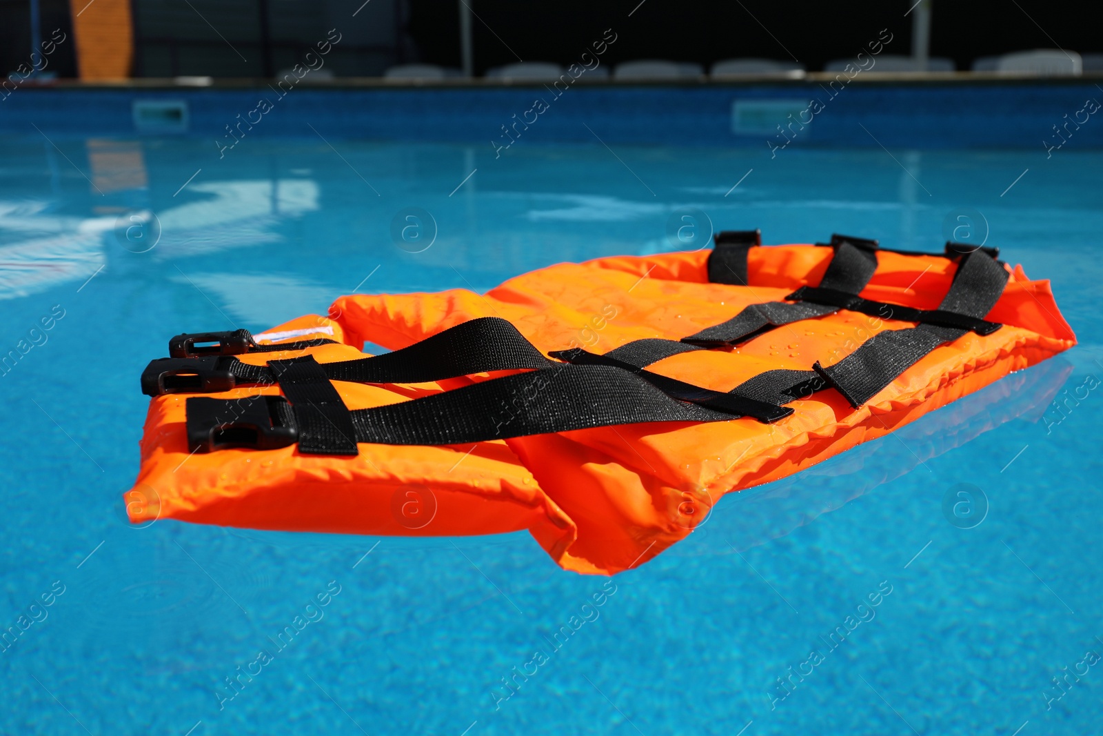 Photo of Bright orange life jacket floating in swimming pool