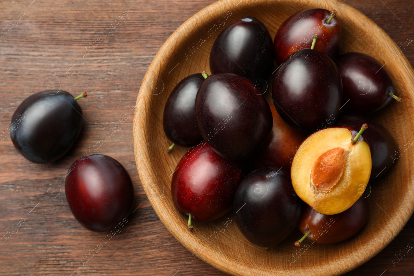 Photo of Tasty ripe plums on wooden table, flat lay