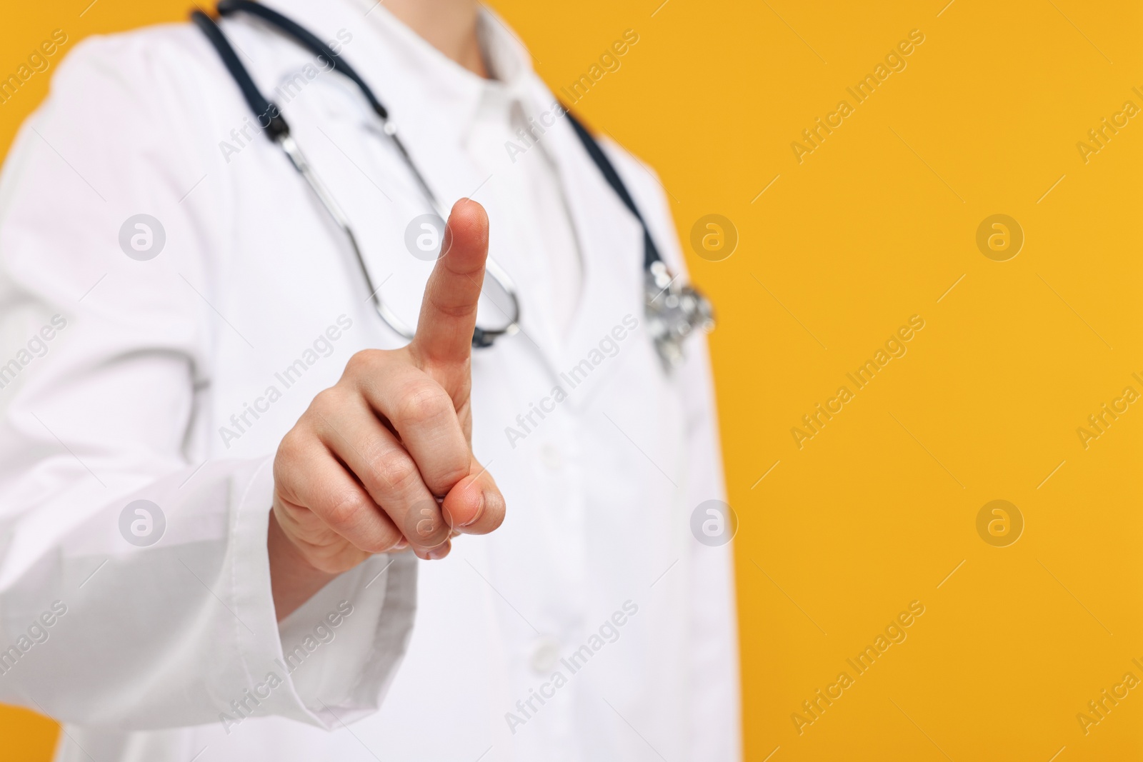Photo of Doctor with stethoscope pointing on orange background, closeup. Space for text