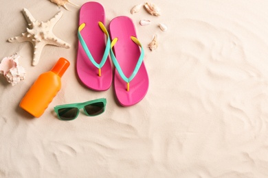 Photo of Different beach accessories on sand, flat lay. Space for text