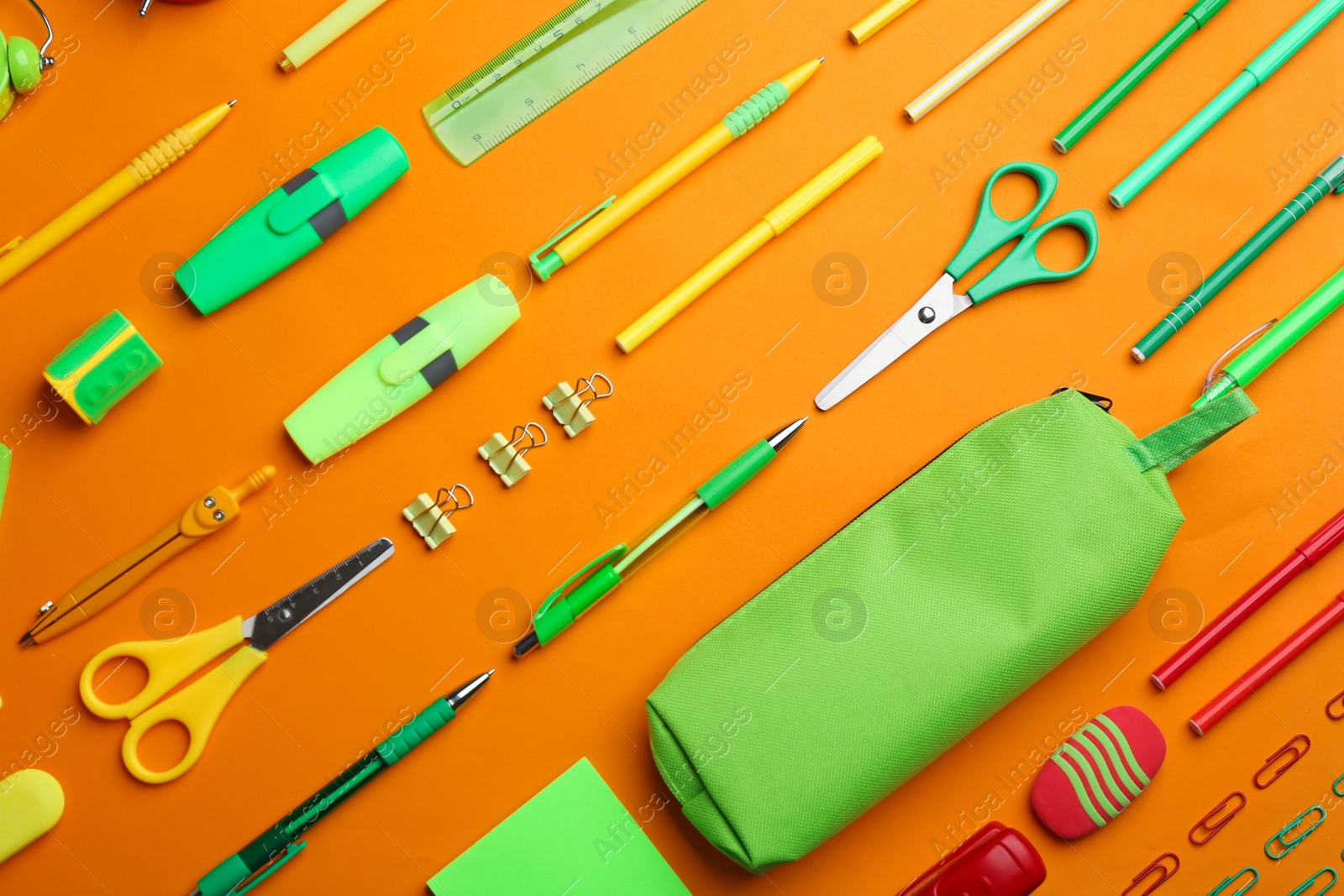 Photo of Different bright school stationery on orange background, flat lay