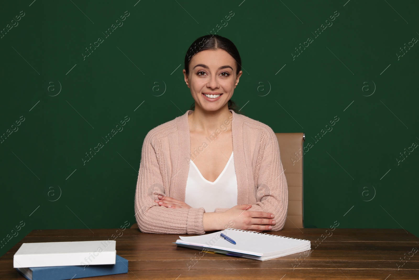 Photo of Portrait of young teacher at table against green background