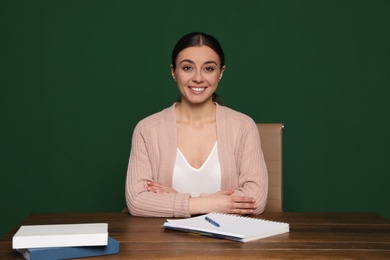 Photo of Portrait of young teacher at table against green background