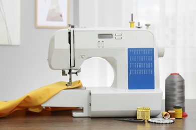 Photo of Sewing machine with fabric and craft accessories on wooden table indoors