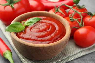 Photo of Bowl of tasty ketchup and ingredients on light grey table, closeup
