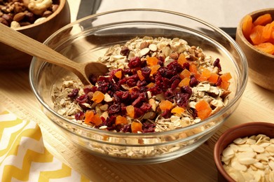 Photo of Making granola. Oat flakes, dried apricots, nuts and cherries in bowl on table, closeup