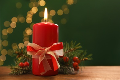 Beautiful Christmas composition with burning candle on table against blurred lights. Space for text