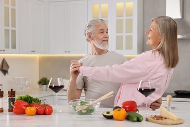 Happy affectionate senior couple dancing in kitchen
