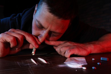 Photo of Drug addicted man taking cocaine at table