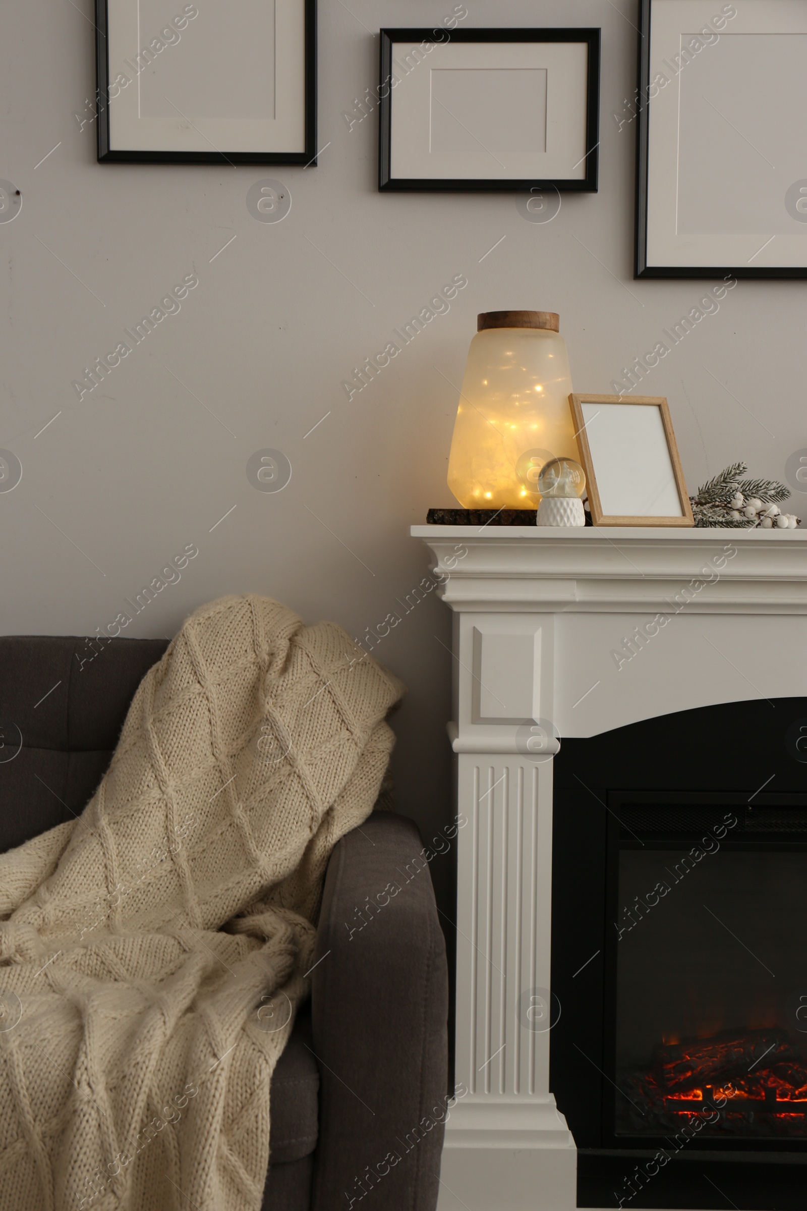 Photo of Stylish interior decorations on fireplace near white wall indoors