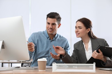 Businesswoman helping intern with work in office