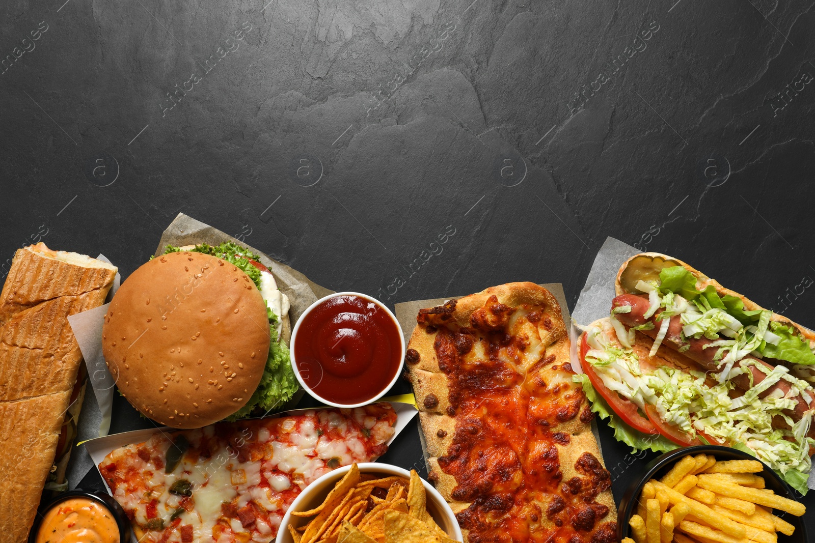 Photo of Burger, pizza and other fast food on black table, flat lay with space for text