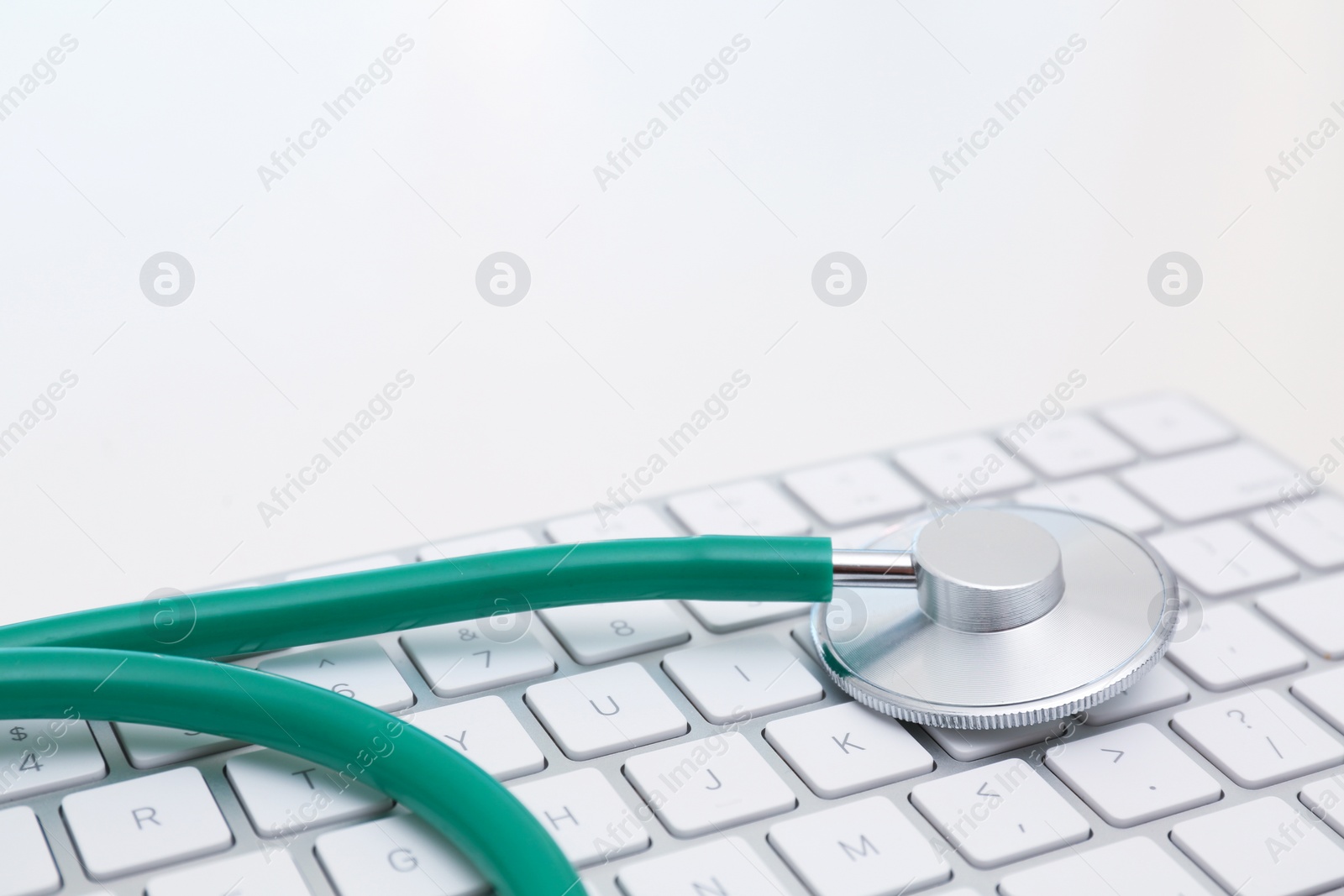 Photo of Modern keyboard and stethoscope on light background. Technical support concept