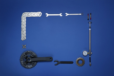 Frame made of different bicycle tools and parts on blue background, flat lay