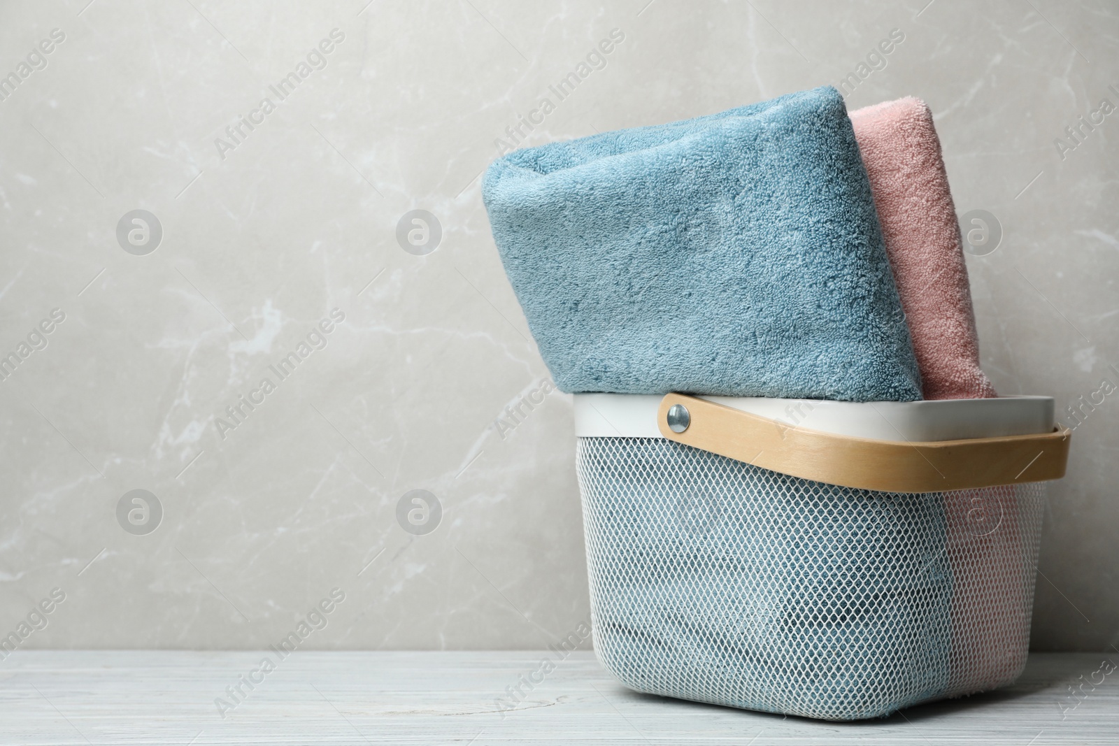 Photo of Basket of fresh towels on table. Space for text