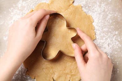 Woman making Christmas cookies with cutter at table, top view