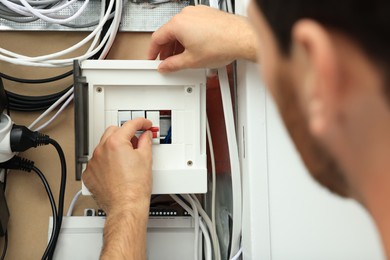 Photo of Electrician switching off circuit breakers in fuse box, closeup