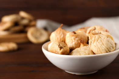 Photo of Tasty dried figs on wooden table, closeup. Space for text