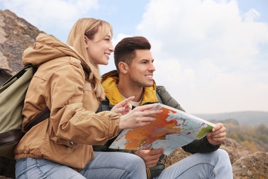 Couple of travelers with backpacks and map enjoying beautiful view on sunny day. Autumn vacation