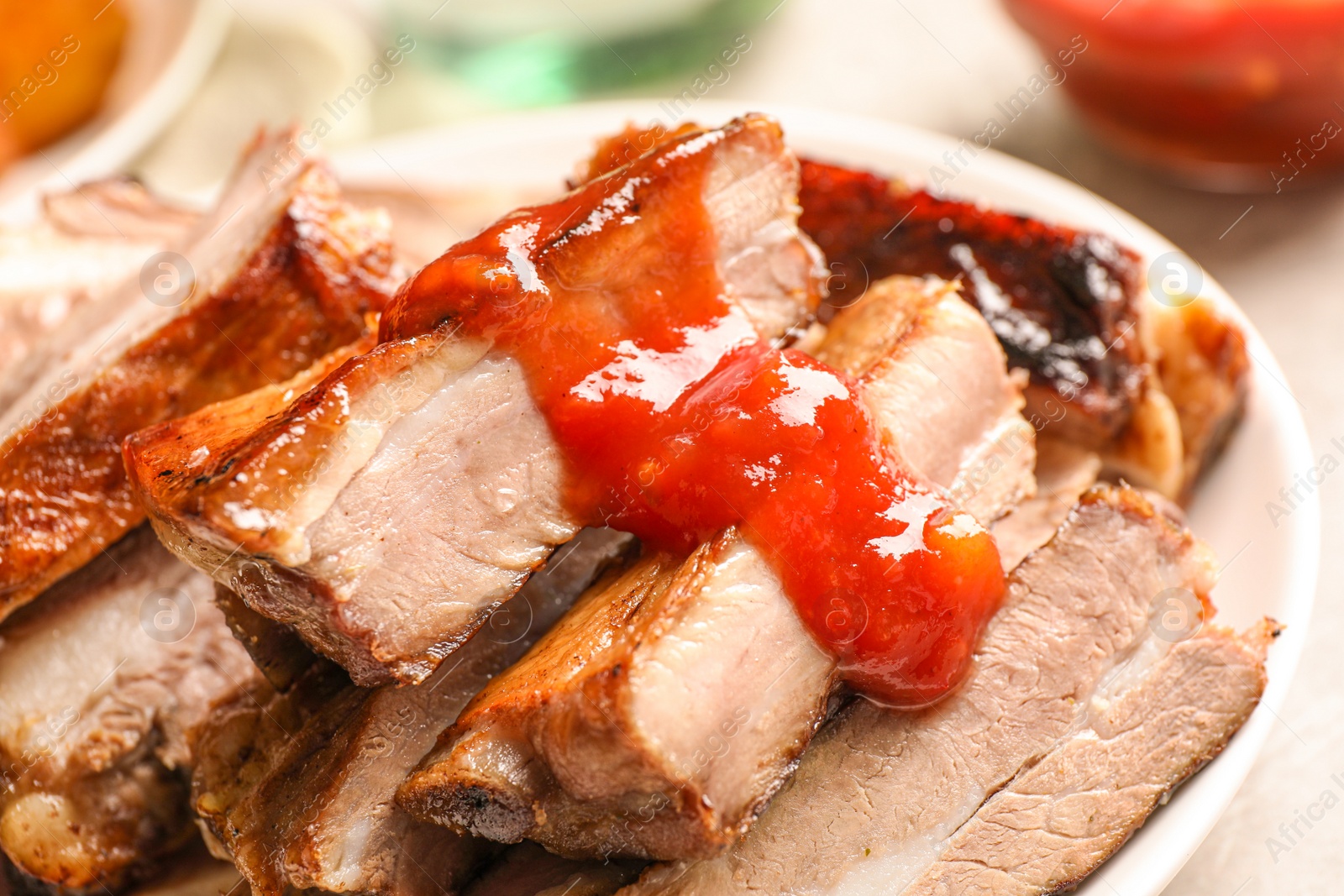 Photo of Delicious grilled ribs with sauce on table, closeup