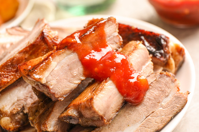 Photo of Delicious grilled ribs with sauce on table, closeup