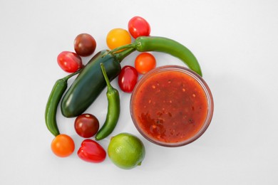 Photo of Bowl with delicious salsa sauce and ingredients on white background, flat lay