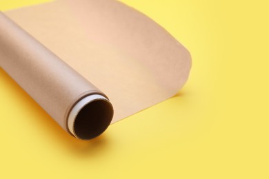 Photo of Roll of baking paper on yellow background, closeup