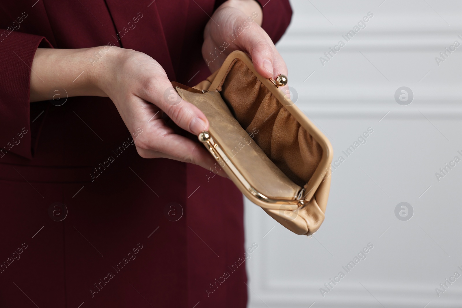 Photo of Woman with empty wallet near white wall, closeup