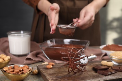 Woman making chocolate cream at table, focus on whisk