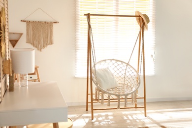 Photo of Comfortable hammock chair in stylish room. Home interior