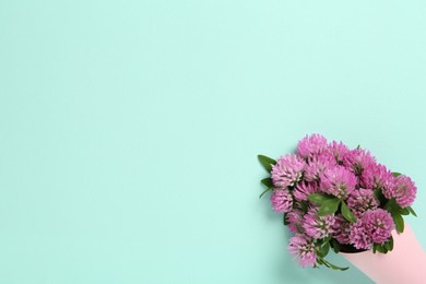 Photo of Bouquet of beautiful clover flowers on turquoise background, top view. Space for text
