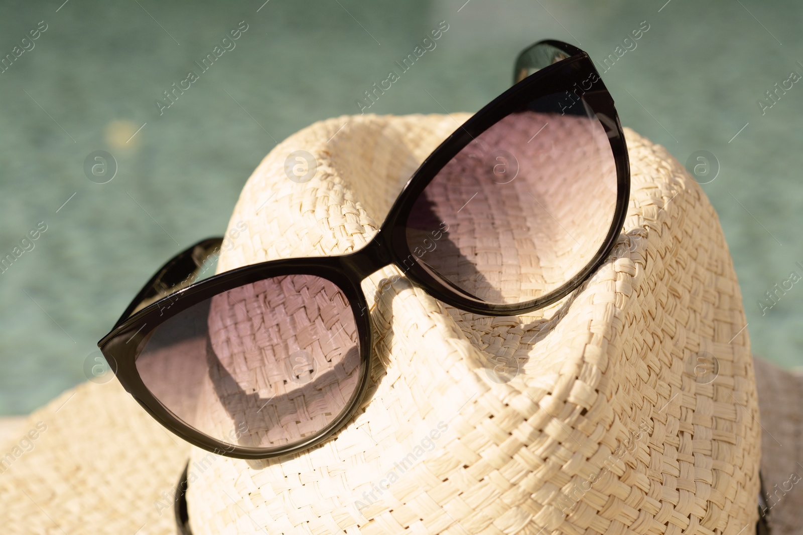 Photo of Stylish hat and sunglasses on blurred background, closeup