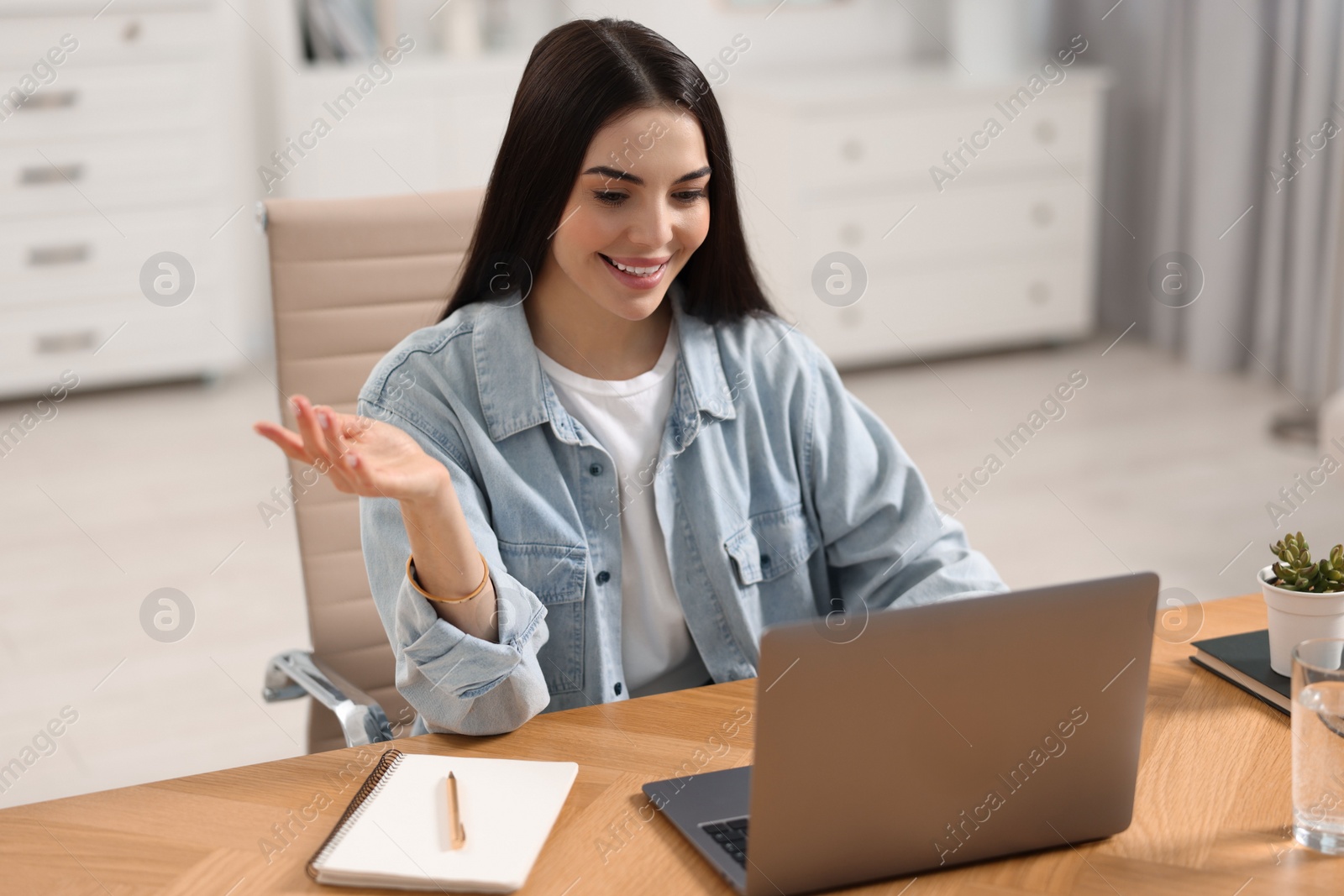 Photo of Young woman using video chat during webinar at table in room