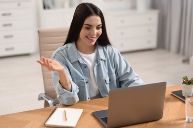 Young woman using video chat during webinar at table in room