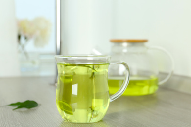 Photo of Cup of aromatic green tea on light wooden table